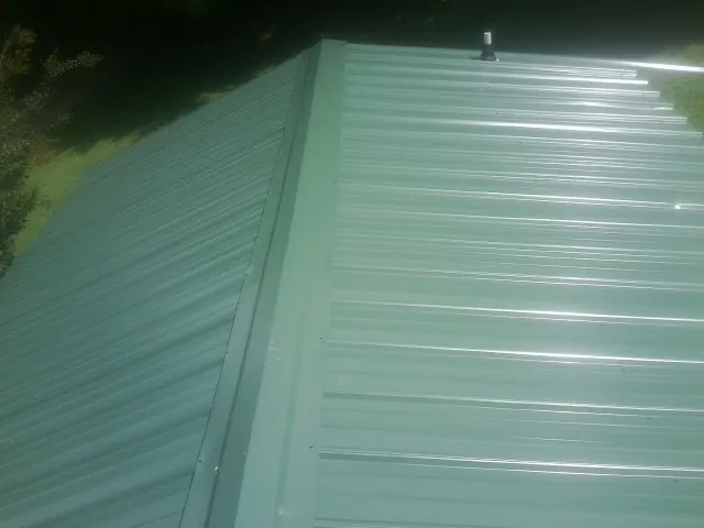 New green metal panels meeting at the ridge of a roof — Flat Roof Repair work by our crew in Orchard