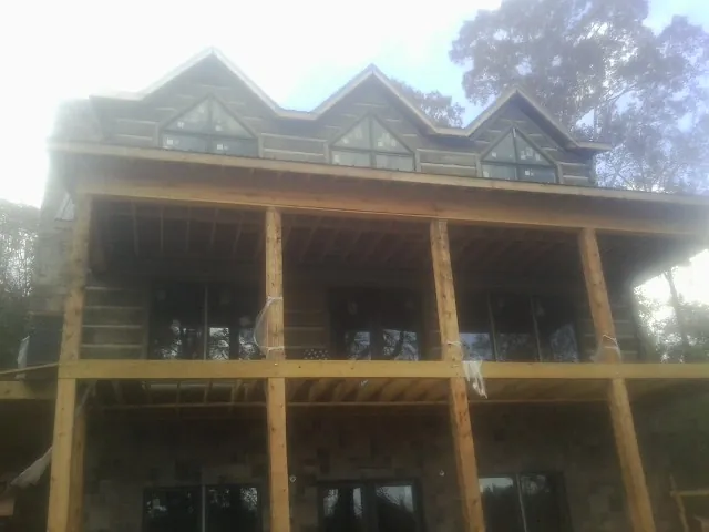 Dormers and porch framing on a large log home under construction — Roof Coating work by our crew in Orchard
