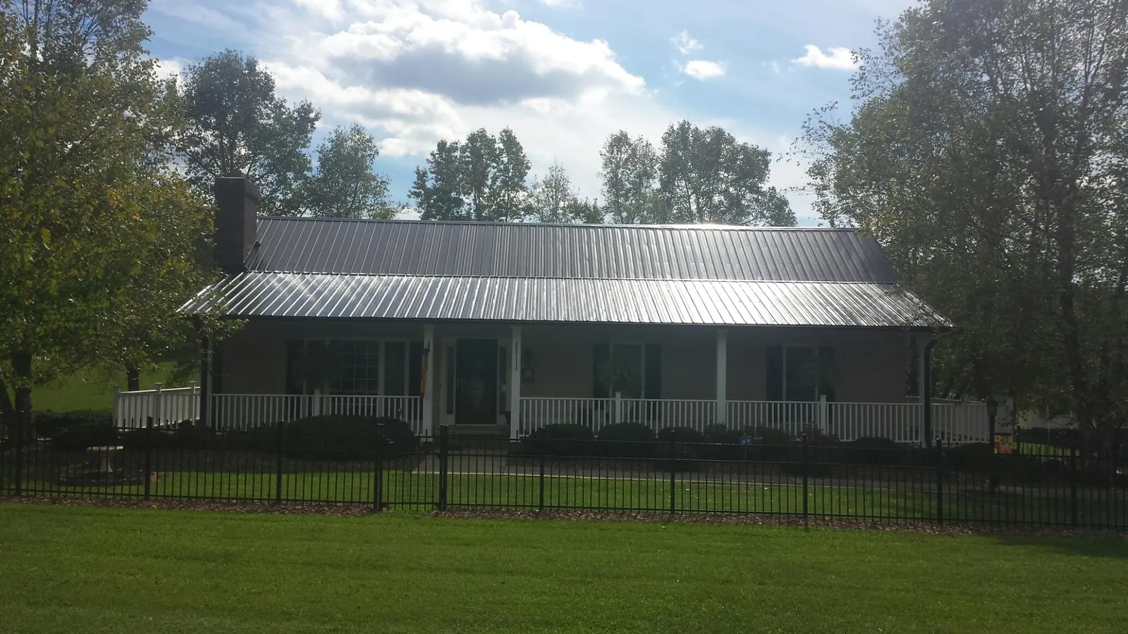 Gray metal roof on a brick ranch with a full width front porch — Gutter Guard Installation work by our crew in Orchard